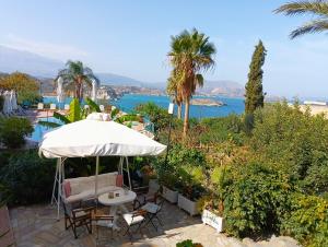 patio z parasolem i krzesłami oraz oceanem w obiekcie Emerald w mieście Plaka