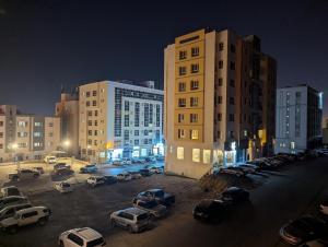 a parking lot with cars in a city at night at Hotel-Style 1BR Near Mall of Oman in Muscat