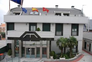 un bâtiment avec deux drapeaux au-dessus dans l'établissement Hostal Los 5 Pinos, à Madrid