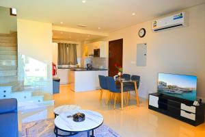 sala de estar con TV y mesa y cocina en Wateera Jebel Sifah-Beachfront, en As Sīfah