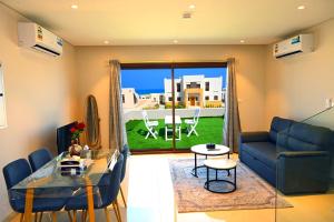 Una sala de estar con un sofá azul y una mesa. en Wateera Jebel Sifah-Beachfront, en As Sīfah