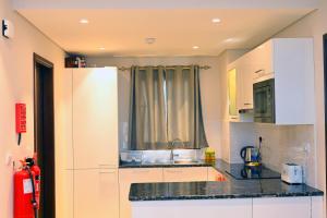 Una cocina con gabinetes blancos y un fregadero. en Wateera Jebel Sifah-Beachfront, en As Sīfah