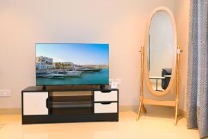 sala de estar con TV y espejo en Wateera Jebel Sifah-Beachfront, en As Sīfah