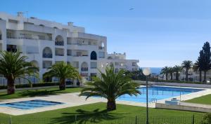 a large white building with a swimming pool and palm trees at Summertime in Porches