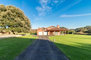 a house on a grassy field with a driveway at Villa Monasterio in Escobedo