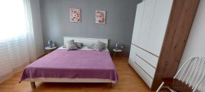 a bedroom with a bed with a purple blanket at Apartman Alenka in Tkon