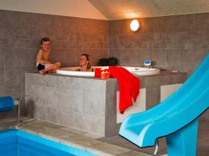Dos personas sentadas en una bañera con tobogán en Luxury Pool Villa by Sea - By Traum Ferienwohnungen, en Høruphav