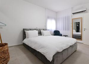 sypialnia z dużym białym łóżkiem i krzesłem w obiekcie אחוזת סנטוריני - וילה מהממת עם בריכה מחוממת מקורה וג'קוזי בעין יעקב w mieście ‘Ein Ya‘aqov