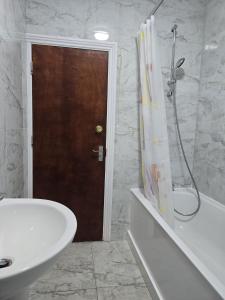 a bathroom with a tub and a sink and a shower at Heathrow roomzzzz BnB in Hayes