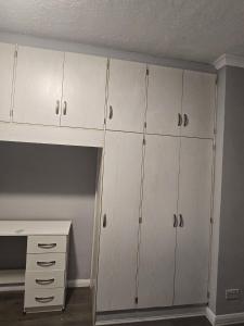 a closet with white cabinets and a desk in a room at Heathrow roomzzzz BnB in Hayes