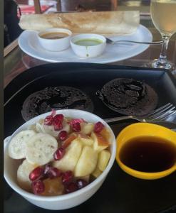 a tray of food with a bowl of fruit and cookies at Halfway Home Hilltop in Gokarna