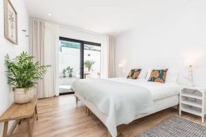 a white bedroom with a large bed and a window at New 2bedroom Apartment w Terrace & Infinity Pool in Olhos de Água +17 photos