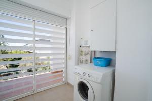 una lavanderia con lavatrice e finestra di Apartment Rosetta, Formosa Village a Fuzeta