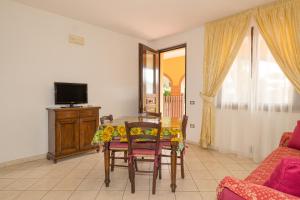 un soggiorno con tavolo, sedie e TV di Il Girasole - Corbezzolo a Venturina Terme