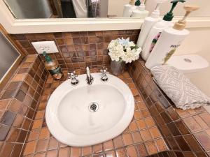 W łazience z podłogą wyłożoną kafelkami znajduje się biała umywalka. w obiekcie Luxury 3BR Home ,Office,Garden,Minutes to Beach w mieście Frankston +27 zdjęć