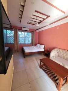 a room with two beds and a tv and a table at Seko Haven Resort in Kilifi