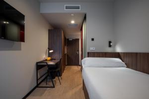 Un dormitorio con una cama y un escritorio y una cama y una habitación. en Lemonade Stays Santiago de Compostela, en Santiago de Compostela