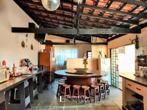 uma cozinha com uma mesa grande e alguns bancos em Chácara c/ Piscina, Churrasqueira com vista linda em Poços de Caldas