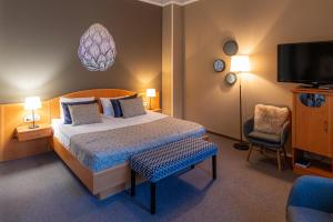 a bedroom with a bed and a chair and a tv at Hotel Piano in Szeged