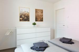 a white bedroom with a bed and a dresser at Apartment unter den Kiefern 93 in Röbel +15 photos
