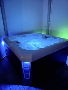 a bath tub with a blue light in a bathroom at KORALIA Domki StandardPlus JACUZZI na wyłączność, BASEN in Sarbinowo