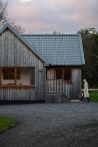 uma mulher caminhando em frente a uma casa de madeira em Kestrel Lodge 3 with Hot Tub em Newton Stewart