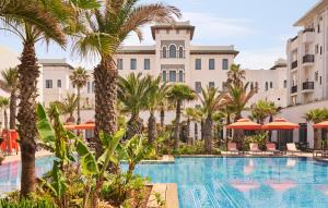 ein Resortpool mit Palmen und Sonnenschirmen in der Unterkunft Four Seasons Hotel Rabat at Kasr Al Bahr in Rabat