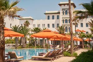 ein Pool im Resort mit Liegen und Sonnenschirmen in der Unterkunft Four Seasons Hotel Rabat at Kasr Al Bahr in Rabat