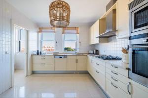 een keuken met witte kasten en een kroonluchter bij Saboia -Spacious Gorgeous Apartment in Monte Estoril