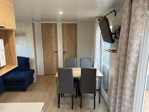 a dining room with a table and a blue couch at Chalet Meerhuus Lauwersoog in Lauwersoog