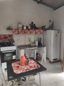 una cucina con tavolo, piano cottura e frigorifero di Raízes kit net a Itacaré
