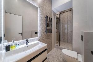 ein weißes Badezimmer mit Waschbecken und Dusche in der Unterkunft Rynok Square Pidzemelya in Lwiw