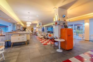 Pestana Alvor South Beach Premium Suite Hotel في ألفور: مطعم مع ثلاجة برتقالية وطاولات وكراسي