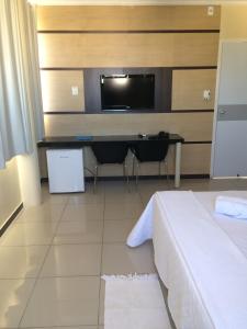 a bedroom with a bed and a desk with a tv at Águas Palace Hotel in Petrolina