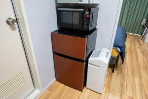 a microwave sitting on top of a dresser with a television at yadobankharuyoshi201 in Fukuoka
