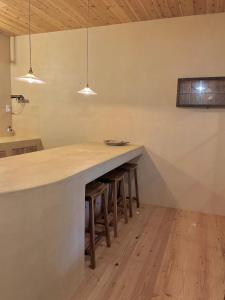 a kitchen with a long counter with stools in it at matai in Kitsuki