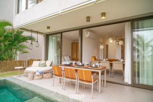 Barra do CamaragibeにあるCasa Duplex à Beira-mar OKA Milagres by Qaviのプールの横にあるテーブルと椅子のあるパティオ