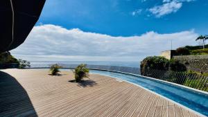 a swimming pool with palm trees on a wooden deck at Sea Front in Câmara de Lobos