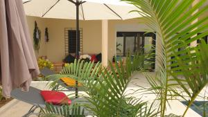 patio con piante e ombrellone di Les Studios de l'Oasis a Ngaparou