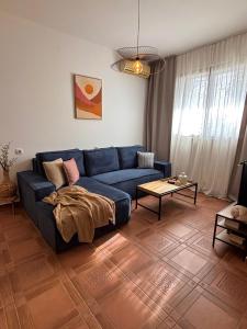 a living room with a blue couch and a table at Flora Apartment - near the sea in Bar, Susanj