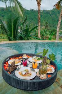 ein Tablett mit Essen auf einem Tisch neben dem Pool in der Unterkunft Astha Bamboo House in Sidemen