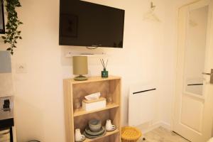 a room with a tv on a wall with a shelf at Charmant Studio avec parking Résidence Zénith in Caen +7 photos