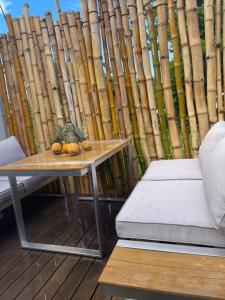 a table and a bench on a deck with a bamboo wall at Le Refuge des Laves in Sainte-Rose