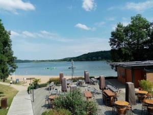 un quai avec des tables et des chaises et un plan d'eau dans l'établissement Le liez, à Peigney