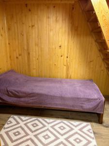 Будинок під Менчулом في راخيف: سرير أرجواني في غرفة خشبية مع سجادة