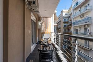 ein Balkon mit Stühlen und Tischen an einem Gebäude in der Unterkunft City Vibe Standard in Thessaloniki
