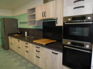 een keuken met houten kasten en zwarte apparaten bij Le relais jeanne d'arc in Cirfontaines-en-Ornois