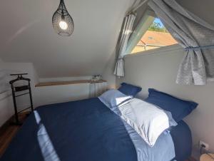 een slaapkamer met een blauw bed en een raam bij Gite du seminaire in Langres