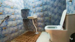 a bathroom with a toilet in a blue tiled wall at Nilaya in Varanasi