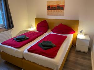 a bedroom with two beds with red sheets and pillows at Traumhaus am See 2 in Rieden
